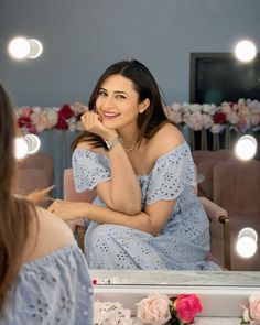 a woman sitting in front of a mirror looking at her reflection