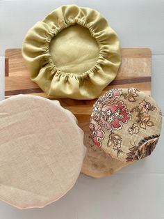 three round cushions sitting on top of a wooden cutting board next to a flowered pillow