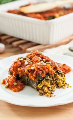 a white plate topped with lasagna covered in sauce next to other food items