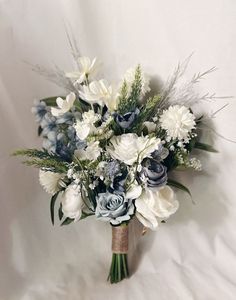 a bridal bouquet with blue and white flowers on a white cloth background for a wedding or special occasion