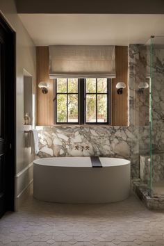 a bathroom with marble walls and flooring next to a bathtub in front of a window