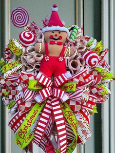 a christmas wreath with candy canes and a gingerbread man in the center is hanging on a door