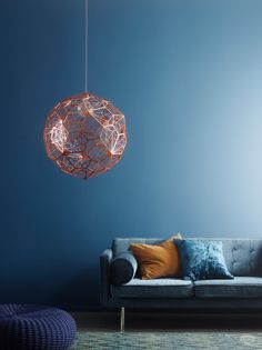 a living room with blue walls and an orange light hanging from the ceiling above it