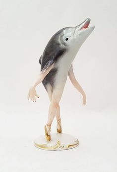 a figurine of a dolphin with its mouth open and legs spread out in the air