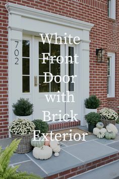 white front door with brick exterior and pumpkins on the steps in front of it