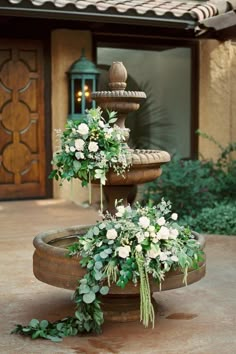 two tiered water fountain decorated with flowers and greenery