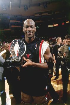 the basketball player is holding his trophy in one hand and smiling at the camera while people look on