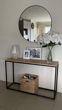 a vase with white flowers sitting on top of a wooden table next to a mirror