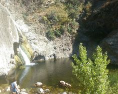 there is a man standing in the water next to a waterfall