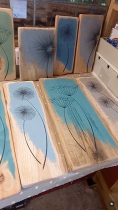 several pieces of wood with dandelions painted on them in blue and green colors