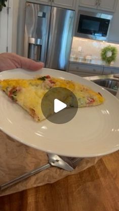 a slice of pizza on a white plate in front of a kitchen counter with stainless steel appliances