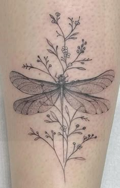 a black and white photo of a dragonfly on the leg with flowers in it