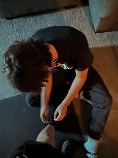 a young boy sitting on the floor playing with a nintendo wii controller