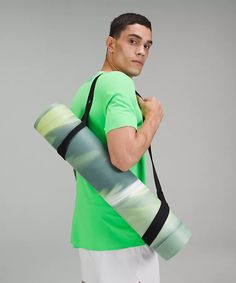 a man is holding a yoga mat and carrying it in his hand while wearing a green shirt