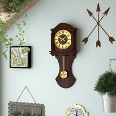 a wall clock mounted to the side of a wall next to a potted plant