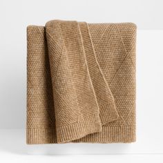 a tan blanket folded on top of a white wall