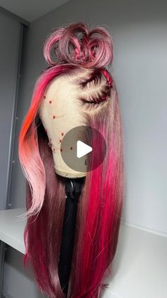 a wig with pink and red hair is displayed on a shelf next to a wall