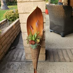 a wooden boat shaped planter with succulents and plants in it sitting on the side of a building