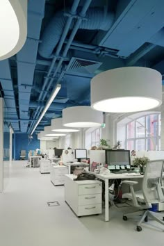 an office with blue ceiling and white desks