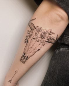 a woman's arm with a cow skull and flowers on it