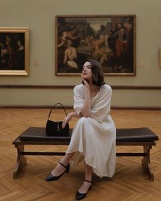 a woman sitting on a bench in an art museum