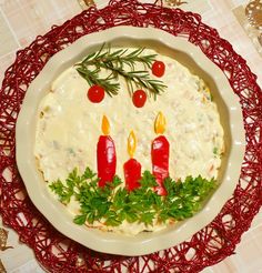 a white plate topped with food and candles on top of a red doily covered table