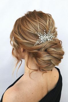 a woman wearing a hair comb with flowers in it's back and her hair pulled up into a low bun