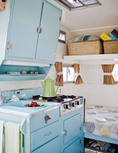 a small kitchen with an oven, sink and bed in the back ground is shown