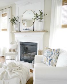 a living room filled with furniture and a fire place in front of a mirror on the wall