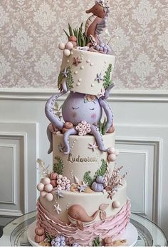 a three tiered cake decorated with animals and flowers