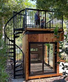 a man standing on top of a wooden structure next to a spiral stair case in the woods