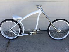 a white bicycle parked in front of a garage door with black rims and spokes