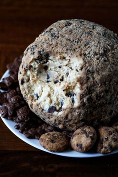 a chocolate chip cookie dough ball on a plate with cookies around it and milk in the background