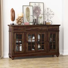 a wooden sideboard with glass doors and pictures on it's top, sitting in a room