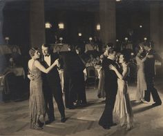 an old black and white photo of people dancing at a formal event with candles in the background