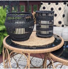 two black wicker baskets sitting on top of a table next to a chair and ottoman