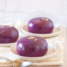 two purple desserts with gold flecks on them are sitting on white plates