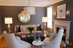 a living room filled with furniture and a fire place in front of a mirror on the wall