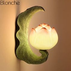 a light that is on the wall next to a vase with a flower in it