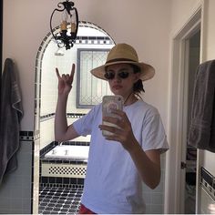 a person taking a selfie in front of a mirror with a hat and sunglasses on