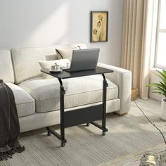 a laptop computer sitting on top of a table next to a couch in a living room