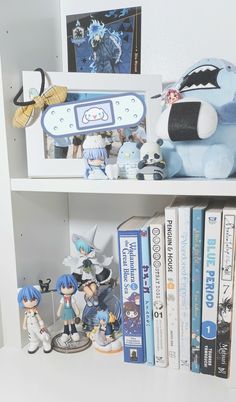 some anime figurines are sitting on a book shelf next to books and dvds