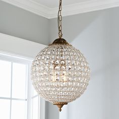 a chandelier hanging from a ceiling in a living room with white walls and windows