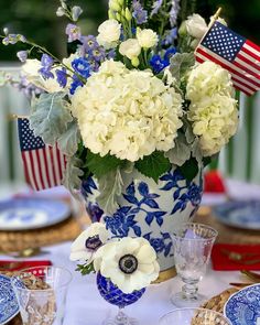 a blue and white vase filled with flowers sitting on top of a table covered in plates