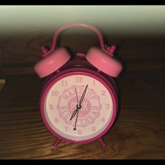 a pink alarm clock sitting on top of a wooden table