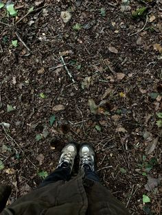 a person standing in the dirt with their feet on the ground and leaves all over them