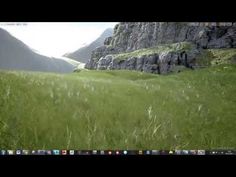 an open laptop computer sitting on top of a lush green field with mountains in the background