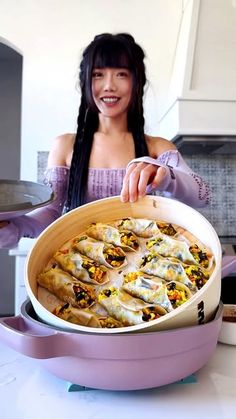 a woman in a purple dress holding a pan filled with food