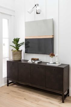 a living room with a large tv mounted on the wall and a potted plant