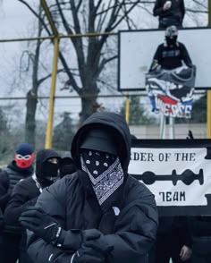 a group of people in black jackets and bandanas standing next to a basketball hoop